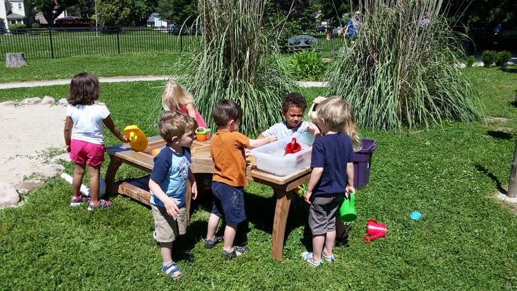 Children playing at a water table outdoors