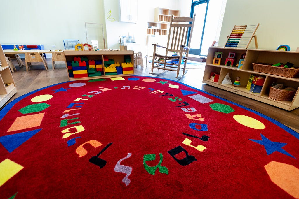 Red rug with colorful shapes and letters in a classroom
