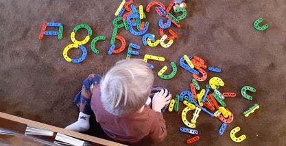 Child playing with colorful letter and shape toys on the floor