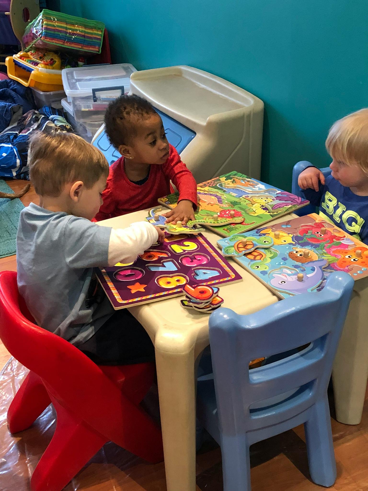 Three children playing with puzzles at a small table