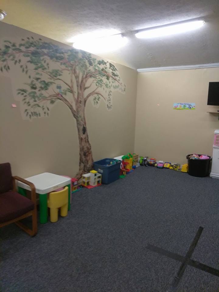 Playroom with a tree mural, toys, and a small table with chairs