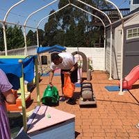 Person cleaning an outdoor play area with a vacuum