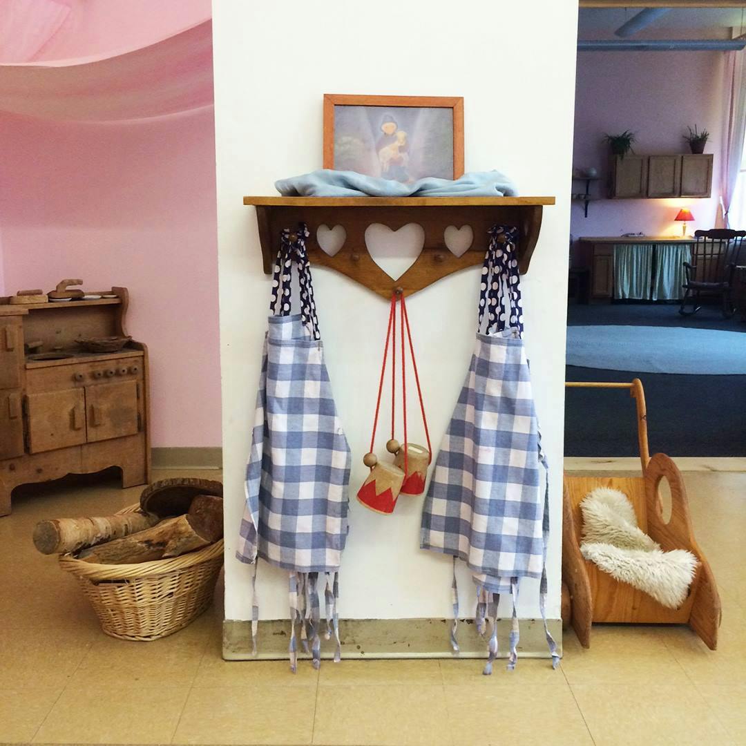 Two blue and white checkered aprons hanging on a wooden rack