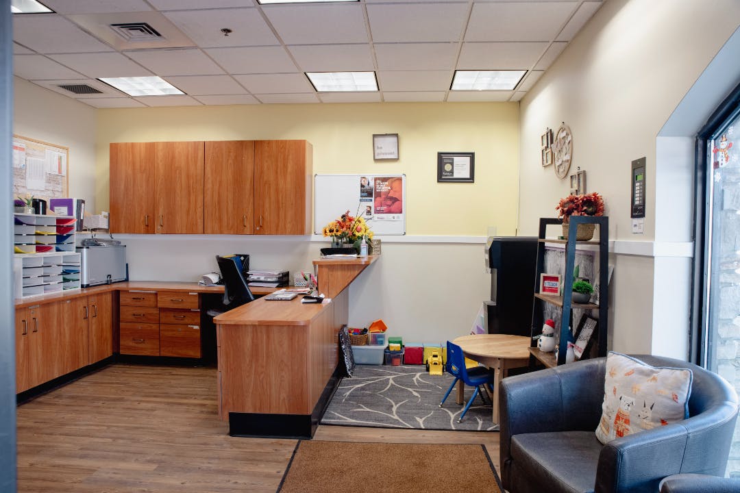 An office reception area with a wooden desk, cabinets, and a small child's table
