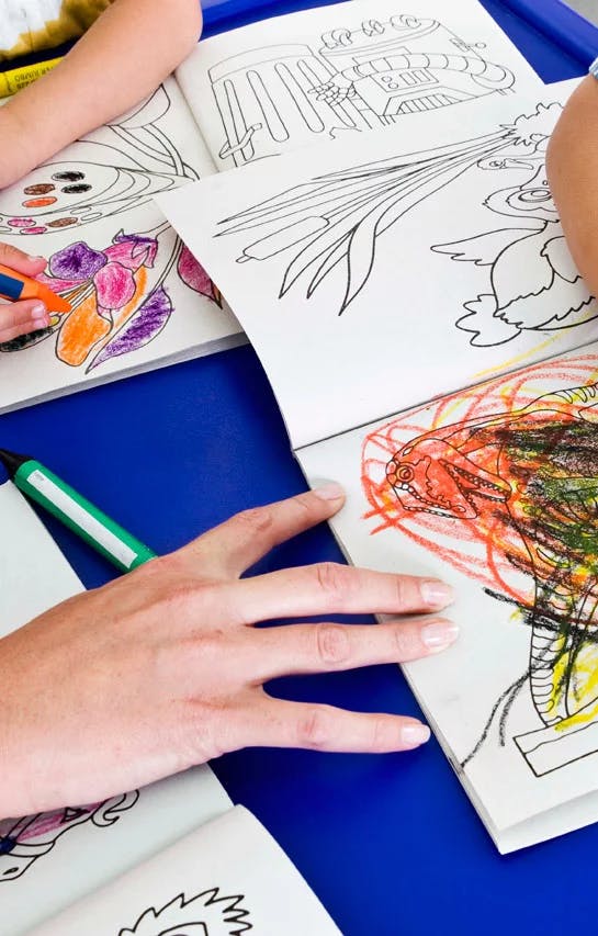 People coloring in coloring books with crayons and markers