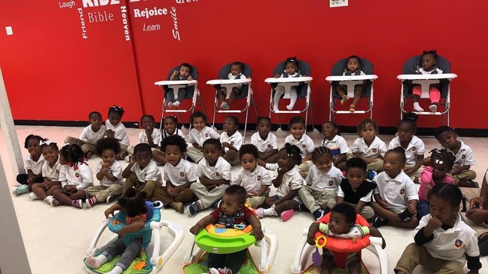 Group of children and babies in high chairs and on the floor