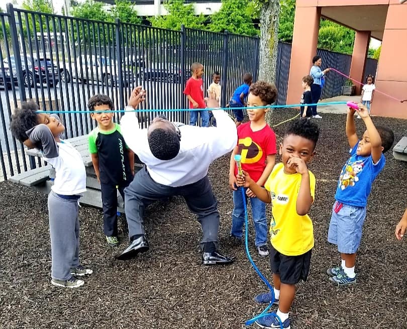 Adult and children playing limbo outdoors
