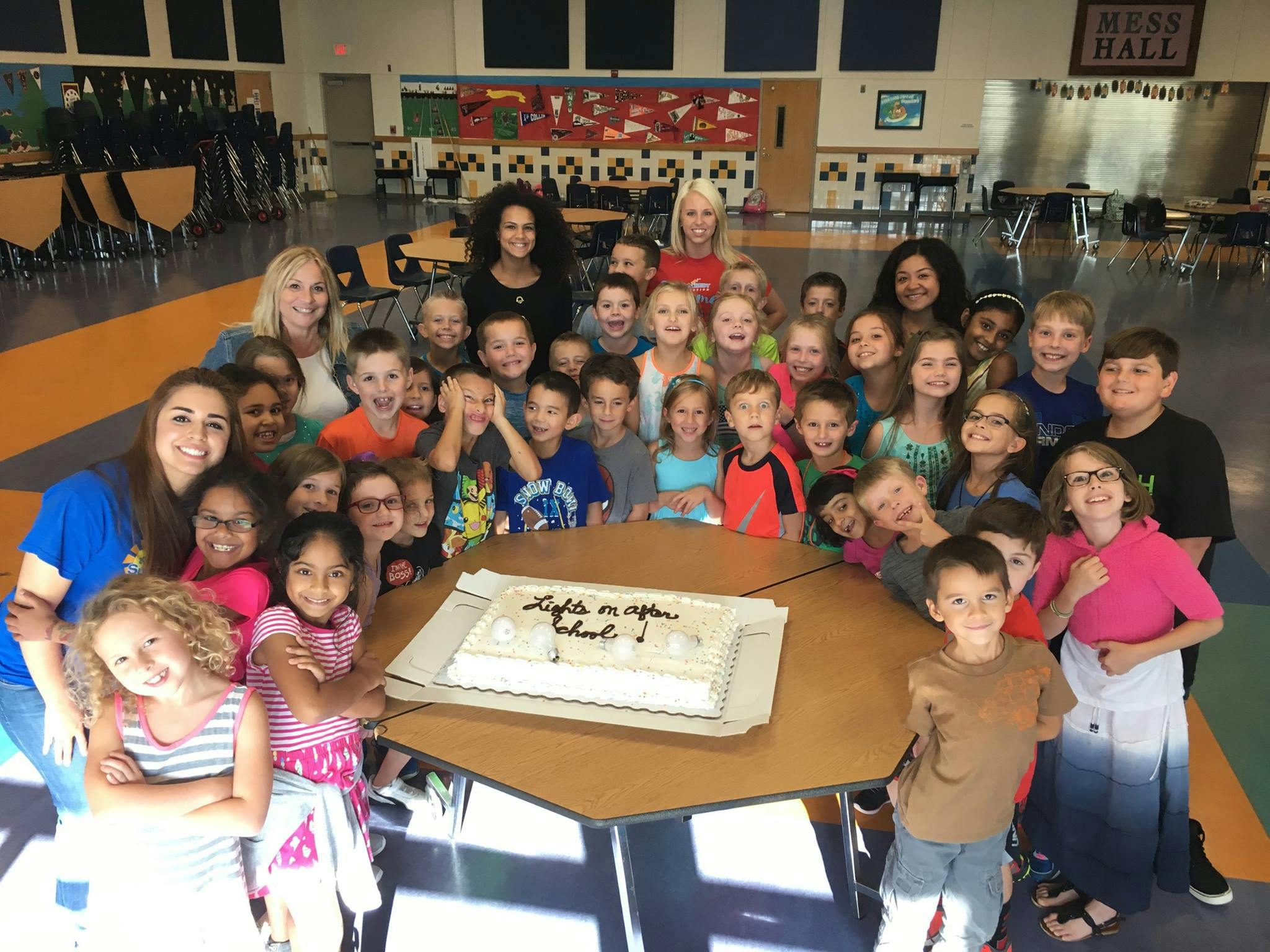 Group of adults and children gathered around a cake on a table