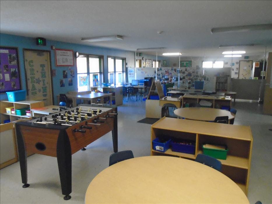 Foosball table in a classroom with round tables and shelving units