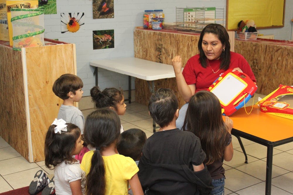 Person showing a drawing toy to a group of children in a classroom