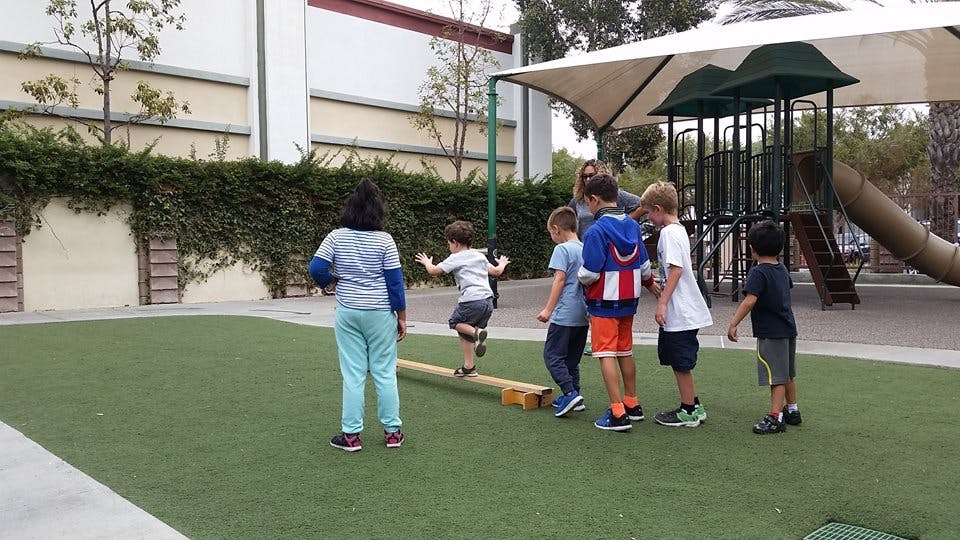 Children playing on a balance beam on a playground