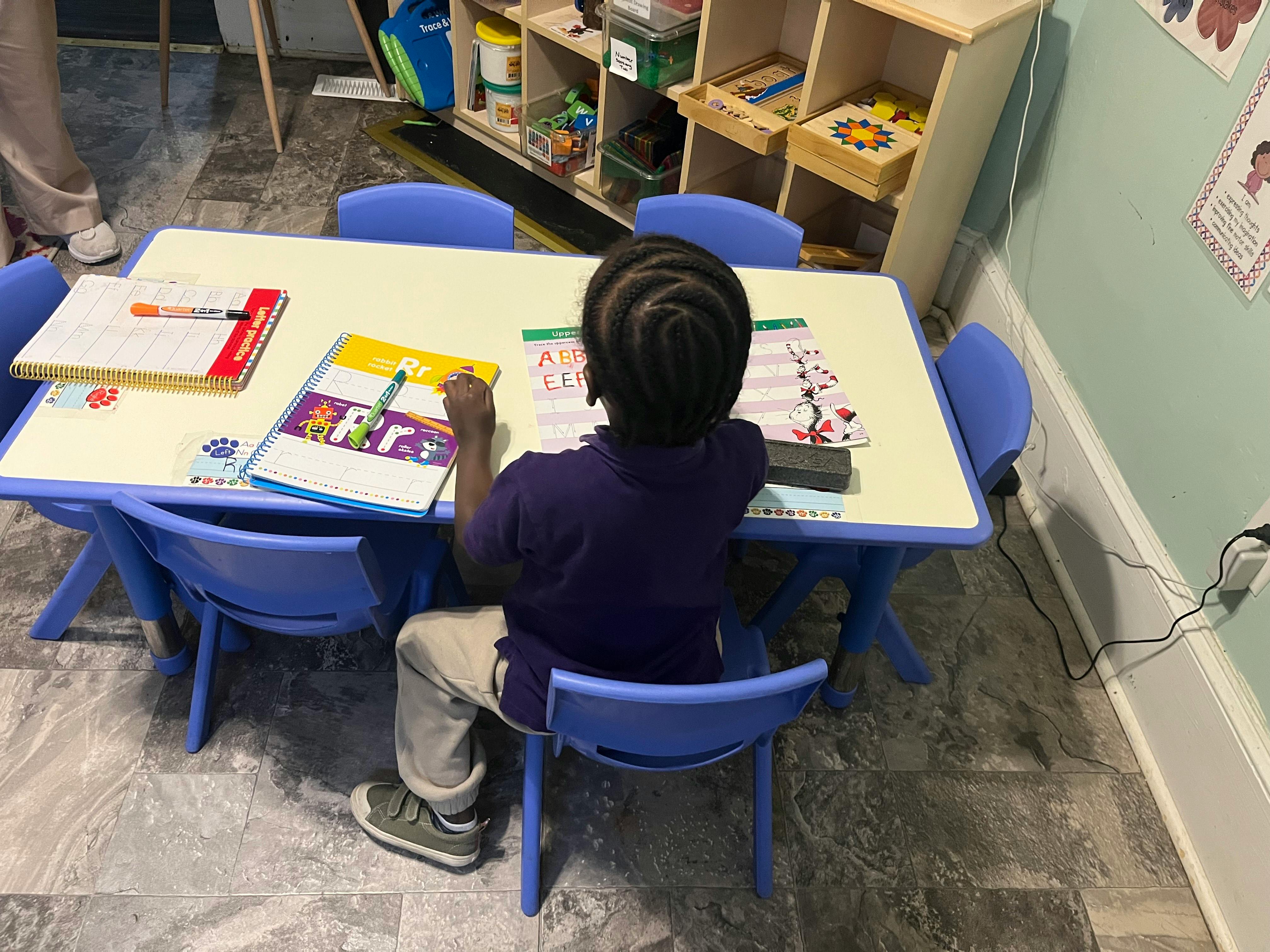 Child sitting at a table with books and writing materials