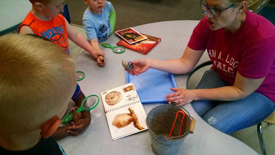 Adult and children at a table with books and magnifying glasses