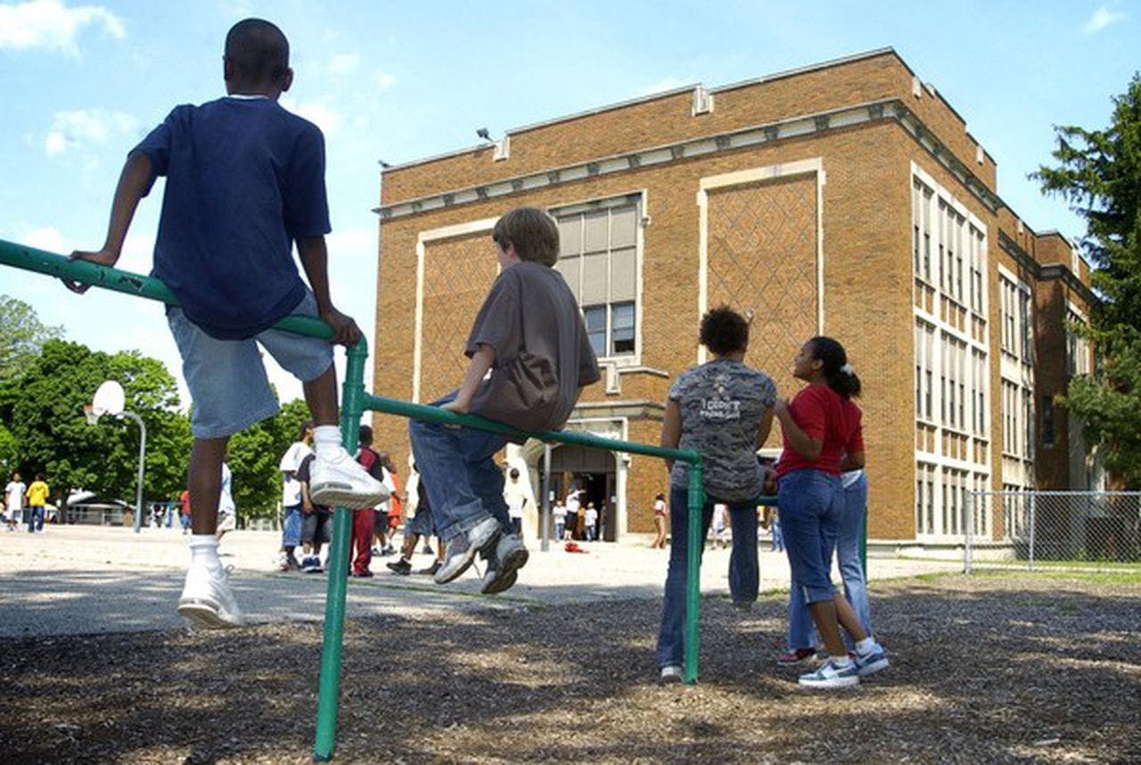 Children on playground equipment in front of a school building