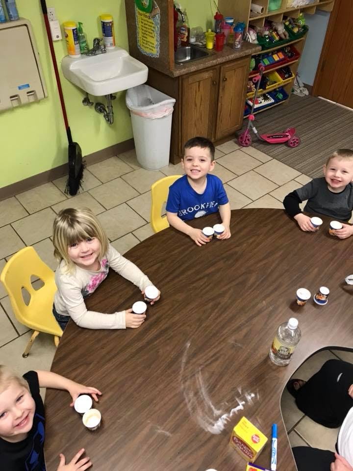 Children sitting around a table with small cups
