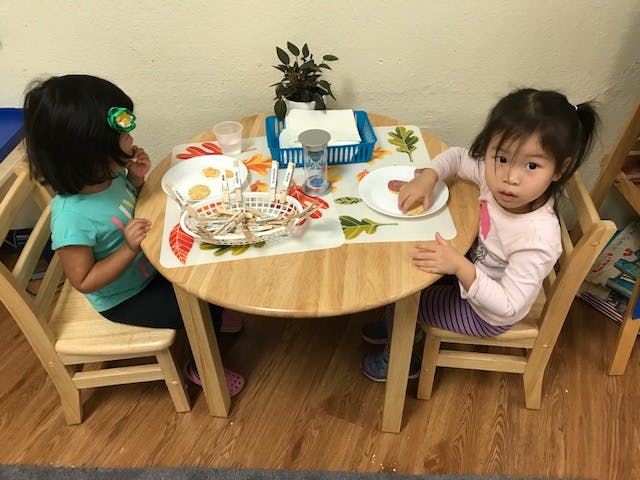 Two children sitting at a table with plates of food