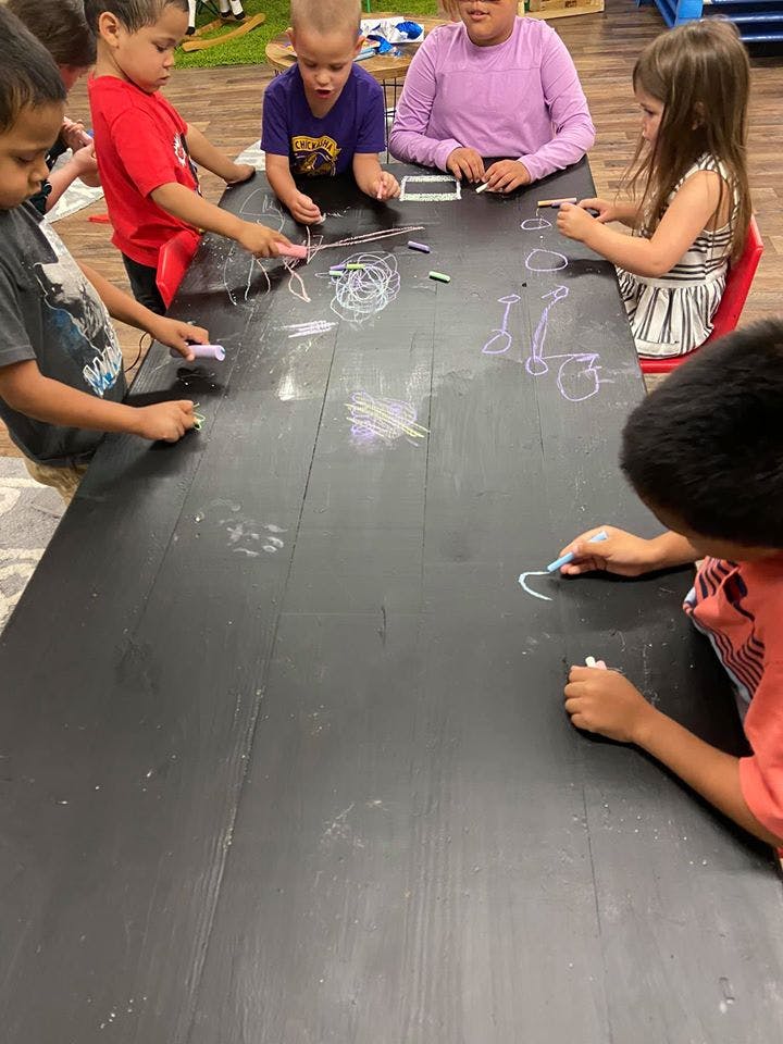 Children drawing with chalk on a large black table