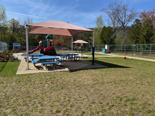 Playground with slides, swings, picnic tables under an awning, and open grassy areas