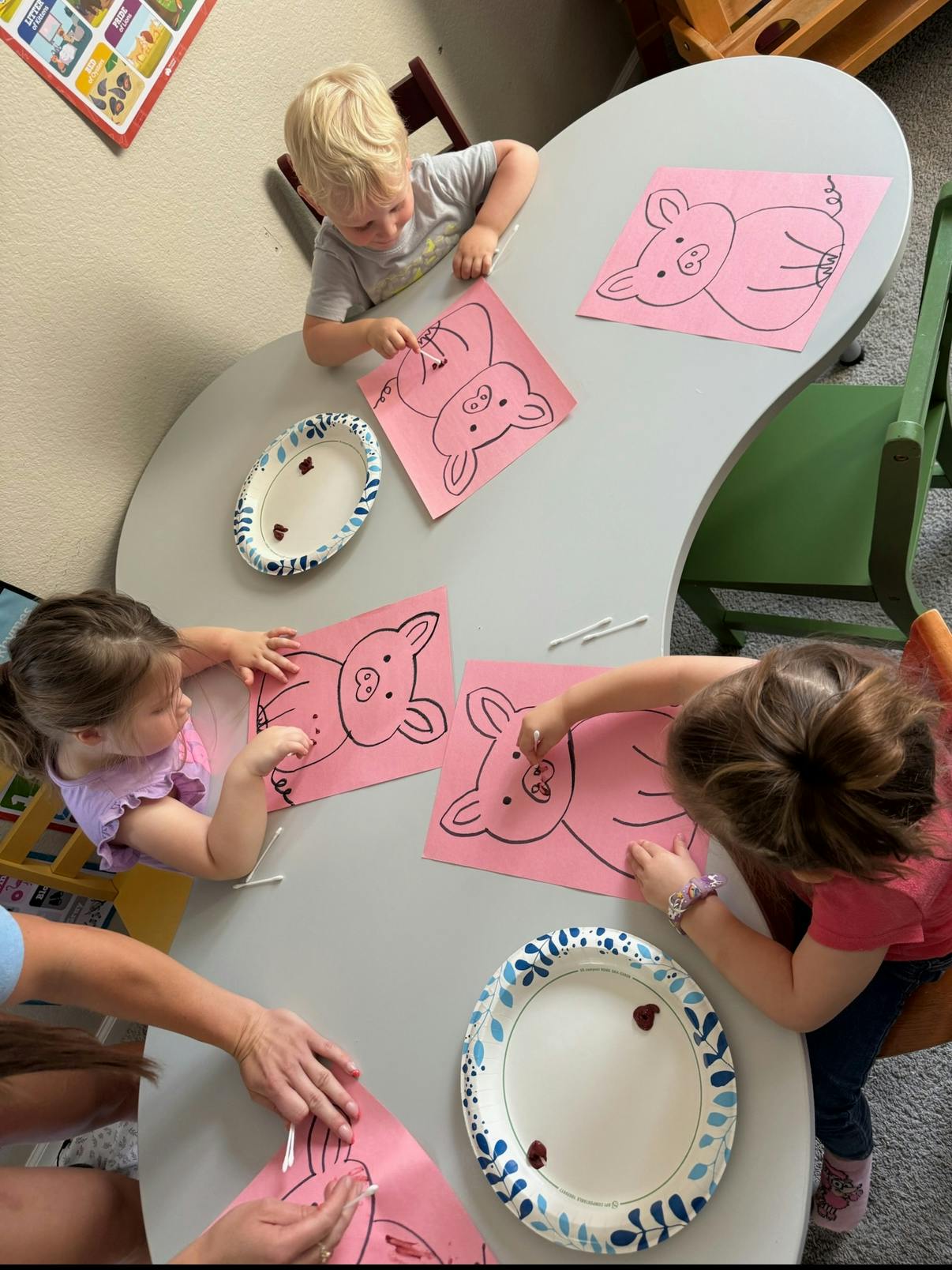 Children coloring pig drawings at a table