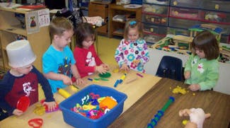 Four children playing with toys at a table