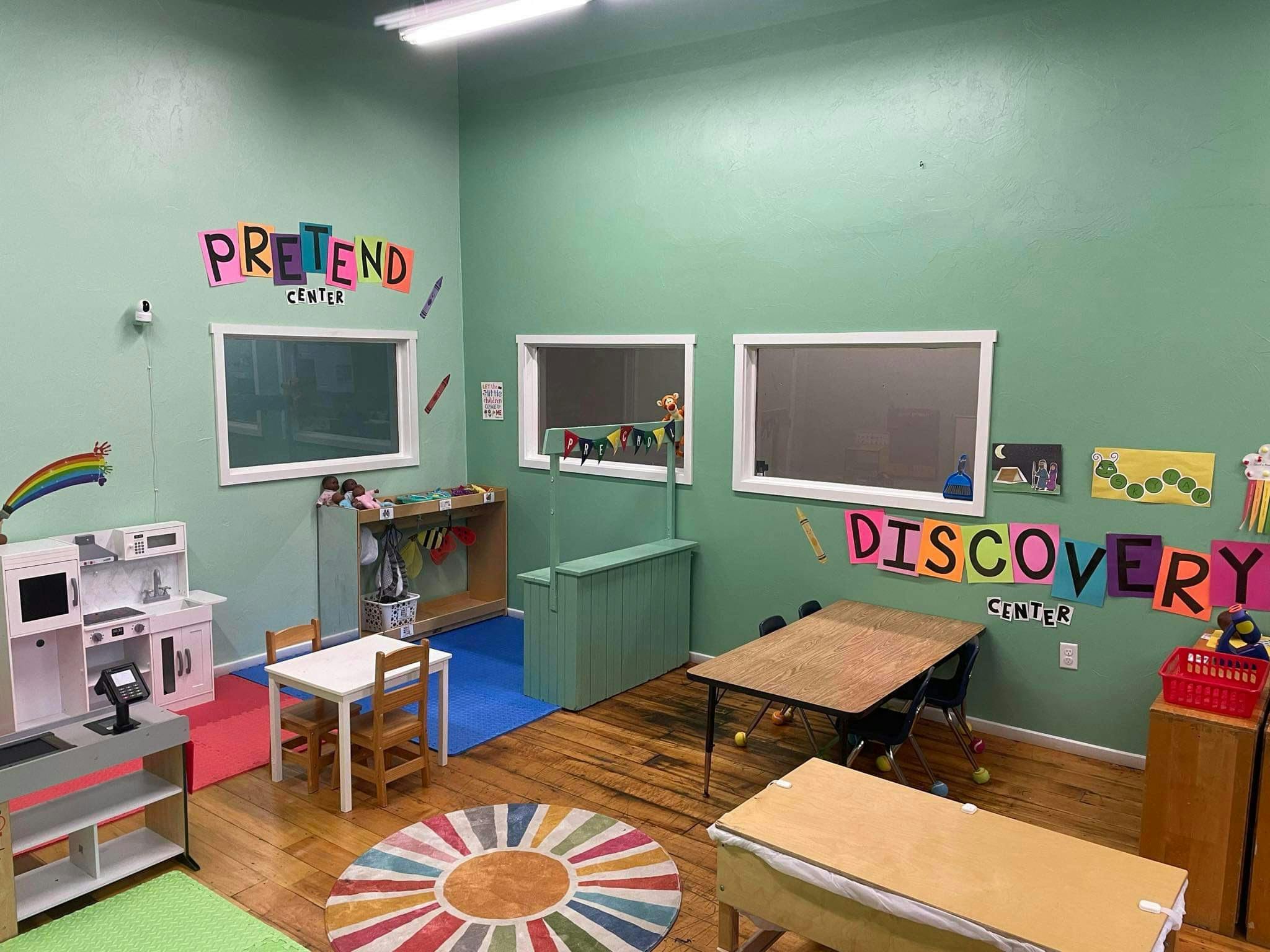 Playroom with pretend kitchen, tables, and colorful wall decorations