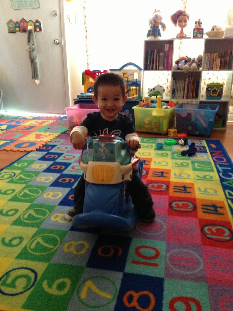 Child sitting on a ride-on toy on a colorful number rug