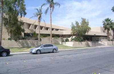 Silver car parked on a street in front of a building with palm trees
