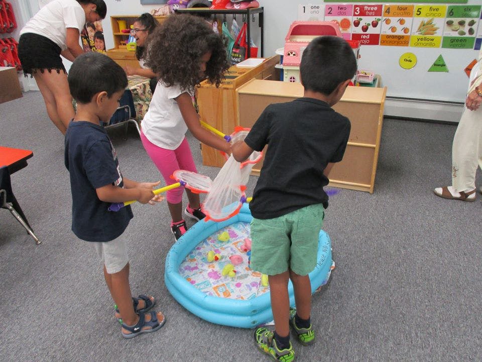 Children playing with nets and a small inflatable pool in a classroom