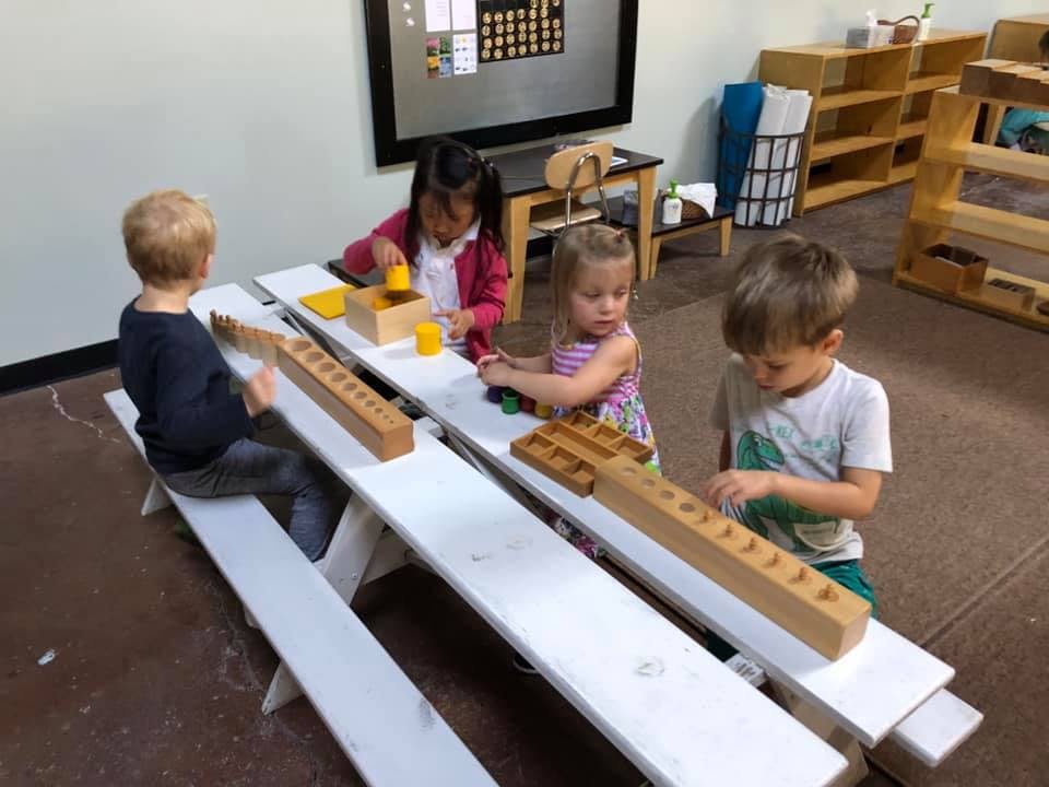 Four children playing with wooden blocks at a table