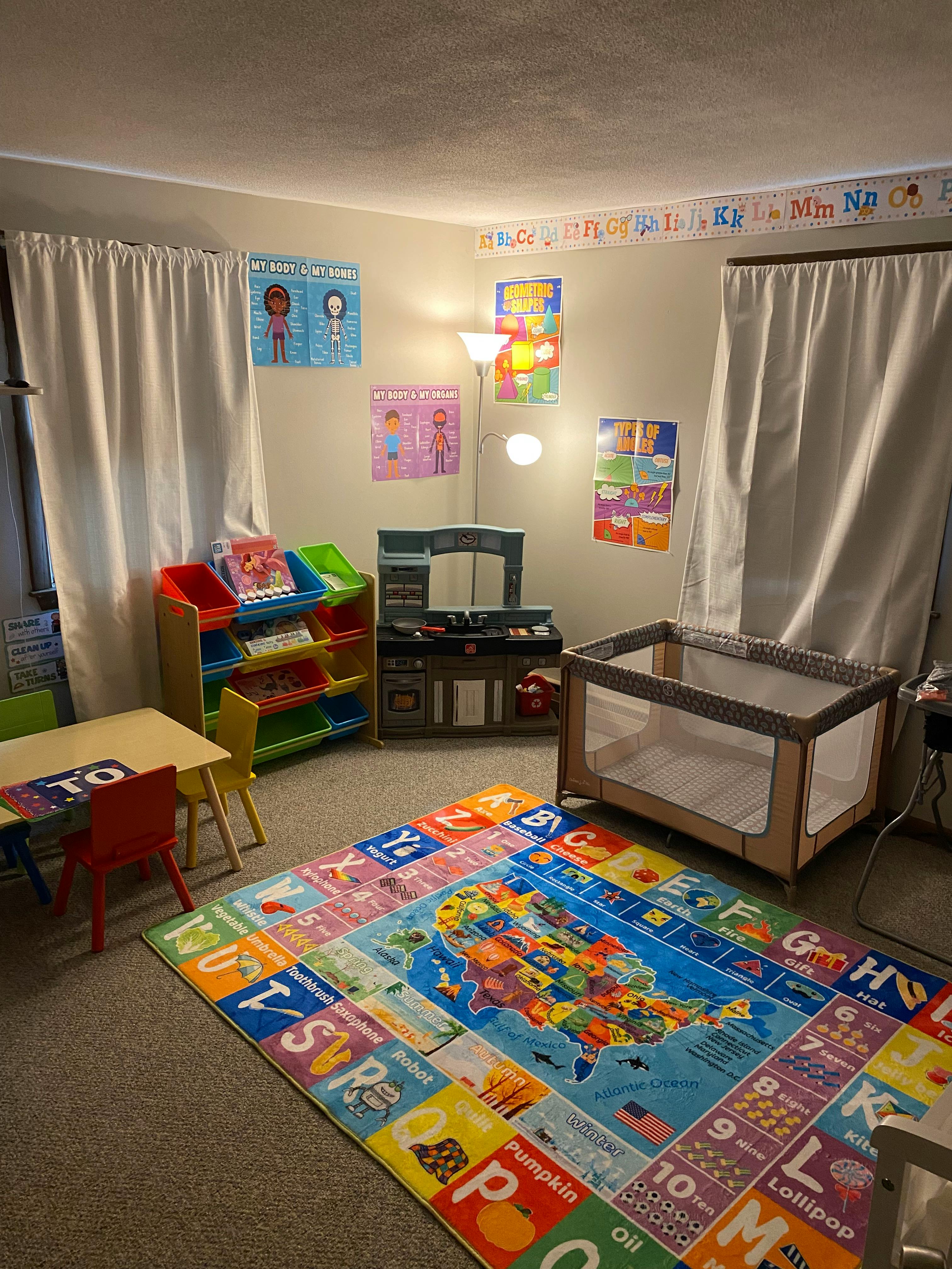 Playroom with a colorful alphabet rug, small table and chairs, and a crib