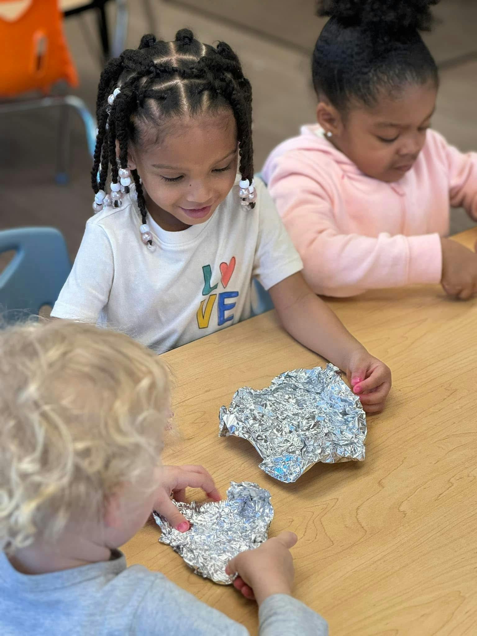 Children at a table playing with aluminum foil