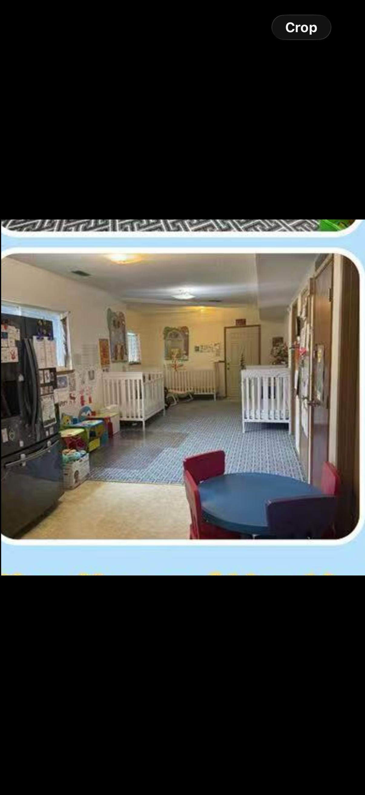 Cribs in a daycare room with a small table and chairs