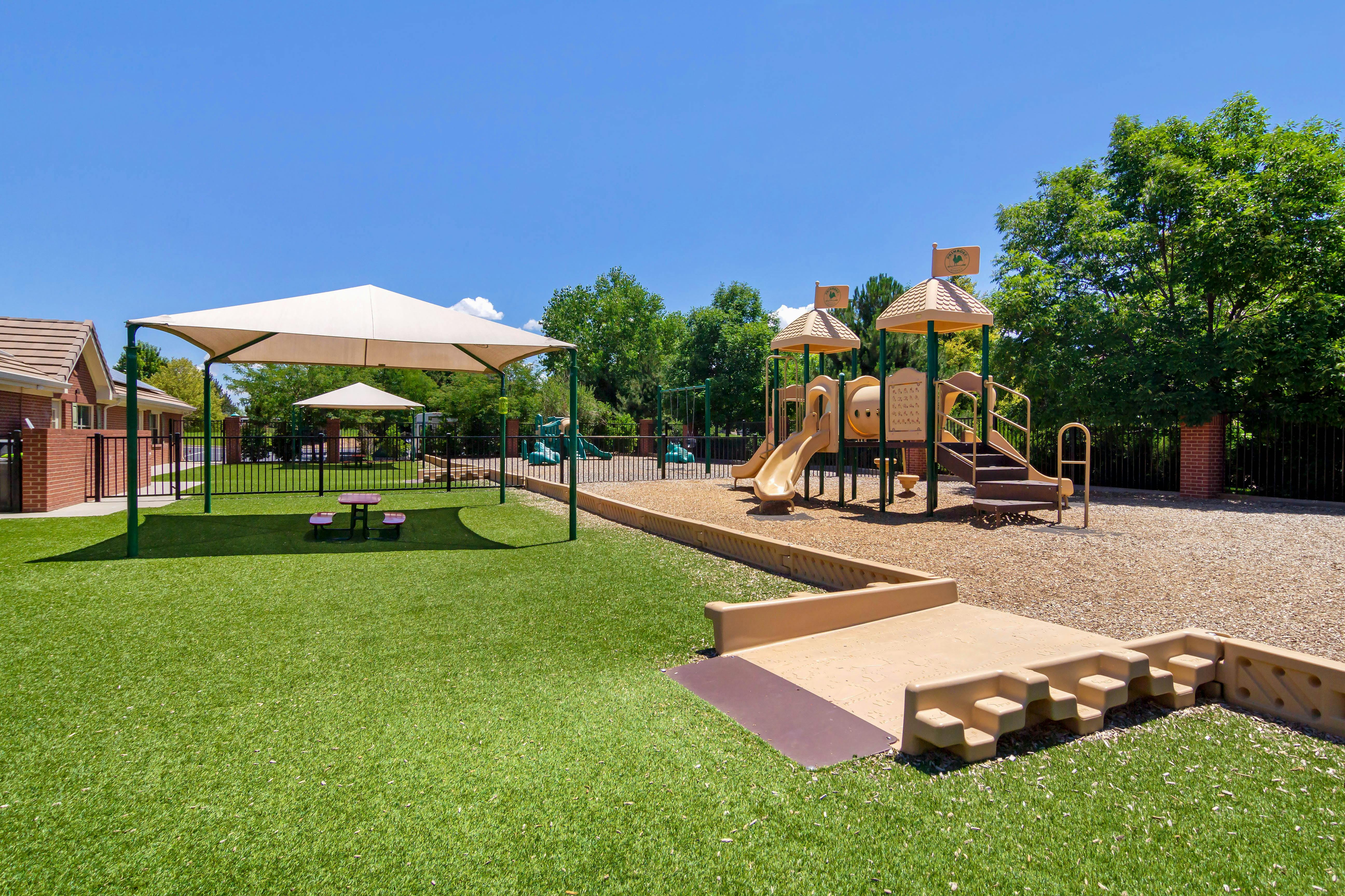 Playground area with artificial turf, shade structures, and play equipment