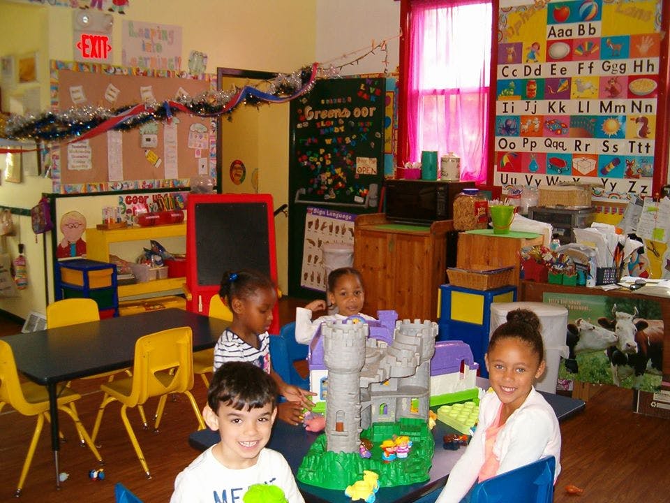 Children playing with a toy castle in a classroom