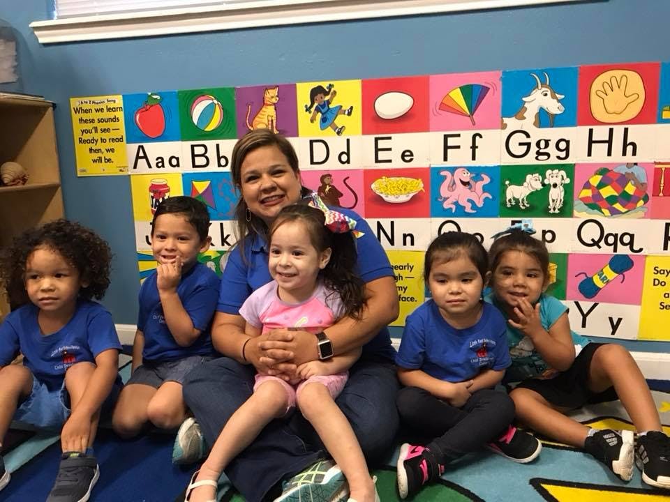 Adult and five children sitting on the floor in a classroom