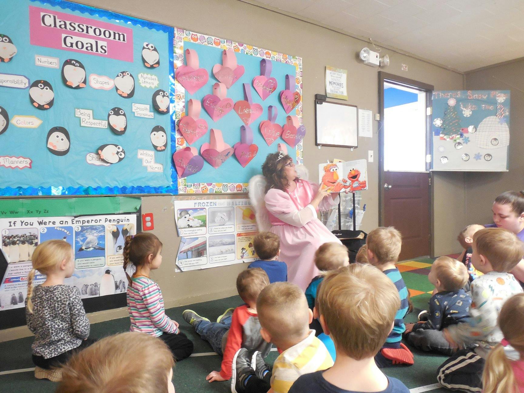 Person reading a book to a group of children in a classroom