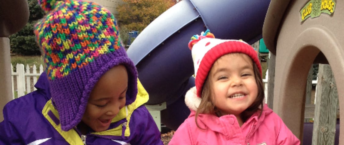 Two children in winter hats on a playground