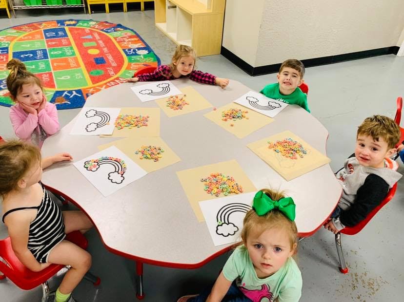 Children sitting around a table with rainbow craft supplies