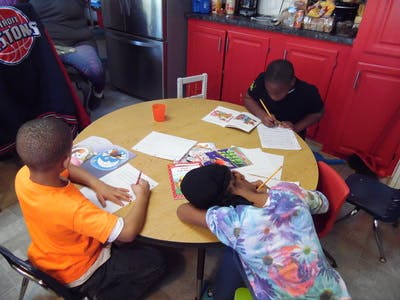 Three children at a round table with books and papers