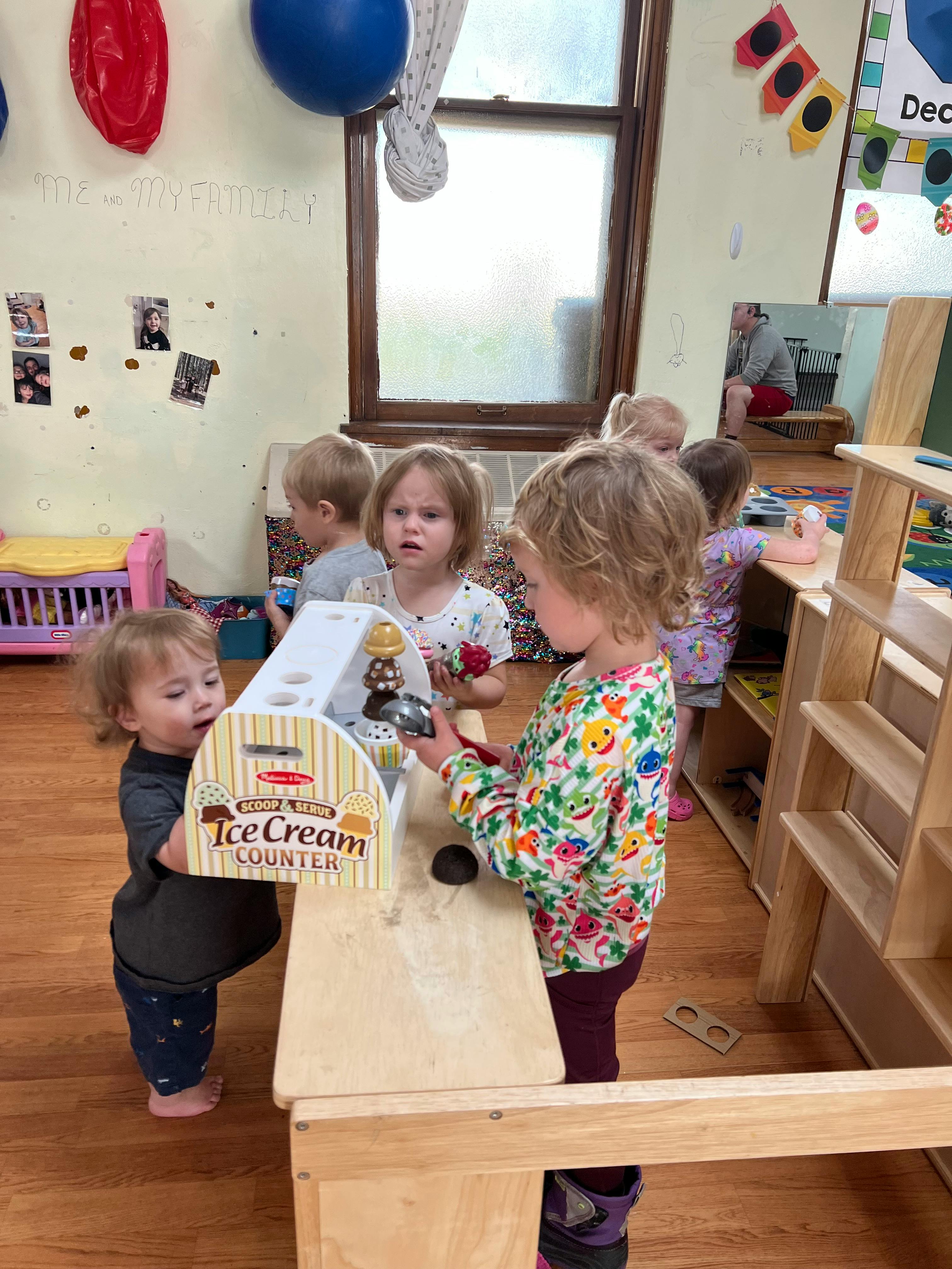 Children playing with an ice cream counter toy in a classroom