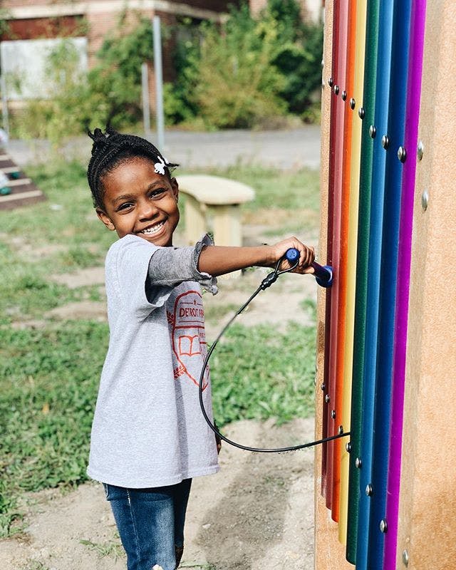 Child playing a colorful outdoor musical instrument