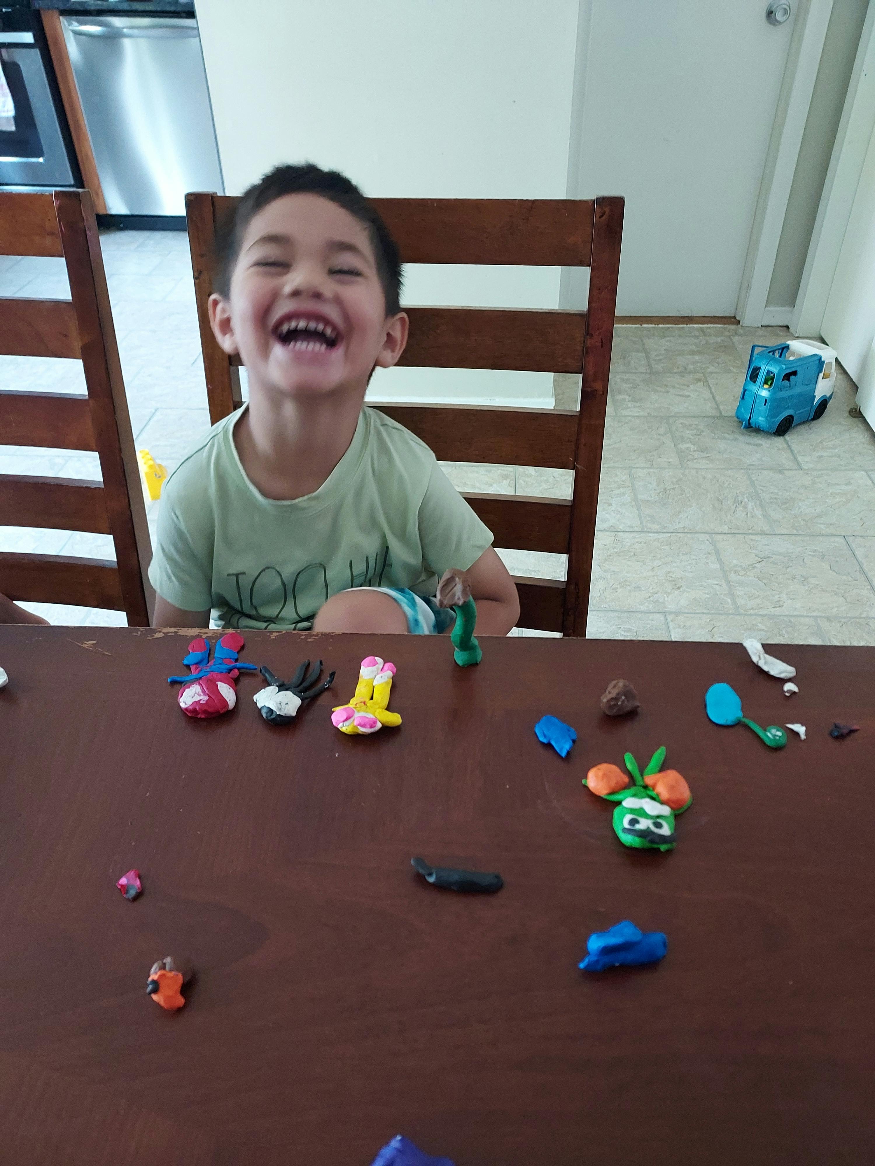 Child sitting at a table with various colorful clay creations