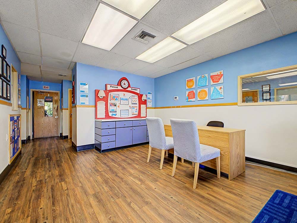 Lobby area of a parent center with a desk, two chairs, and a bulletin board