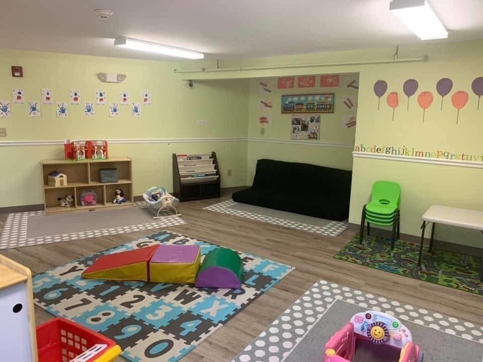 Playroom with colorful rugs, soft play equipment, and a black sofa