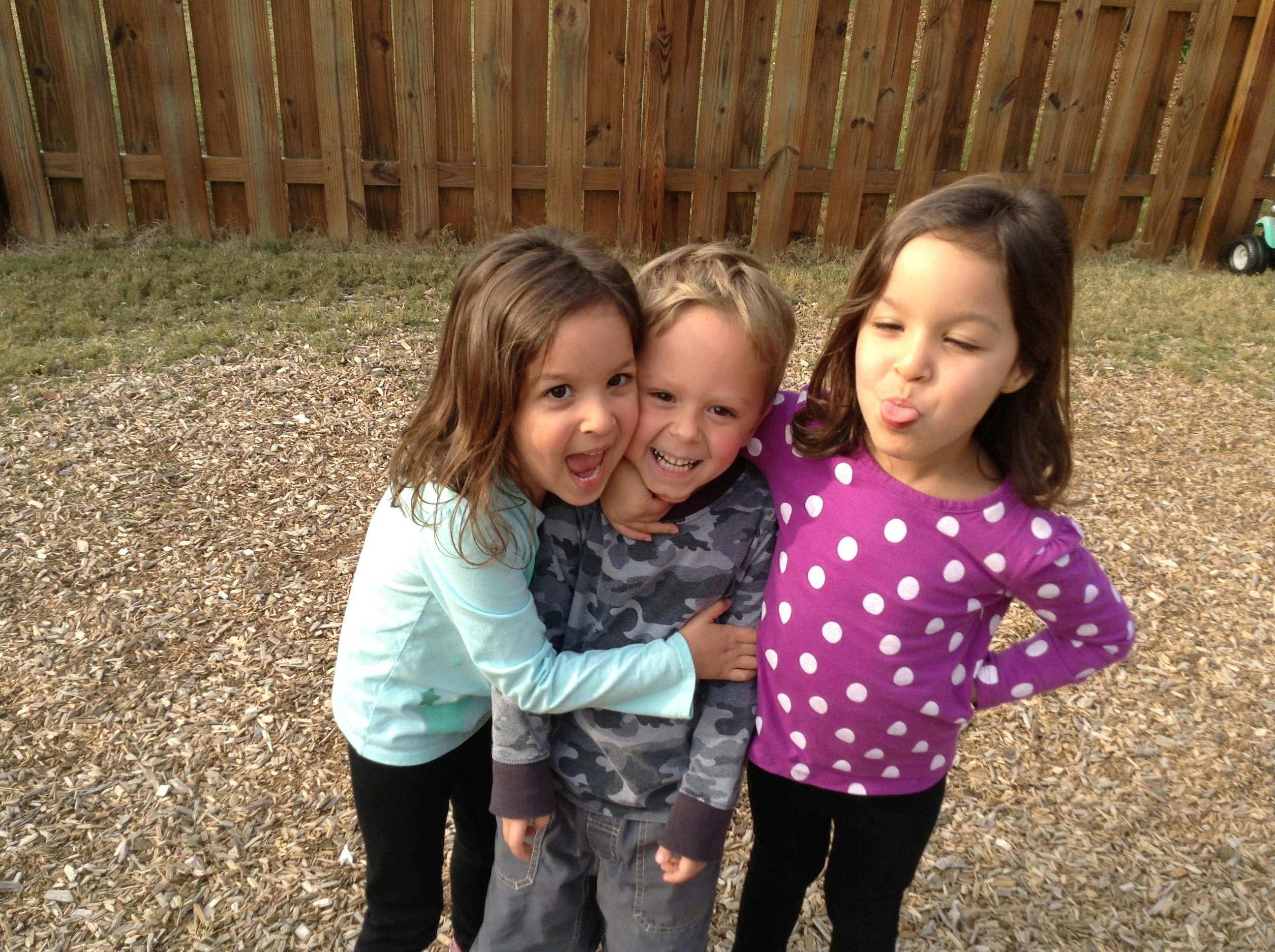 Three children hugging outdoors