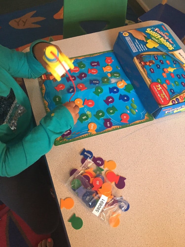 Child playing a fishing game with colorful fish-shaped pieces