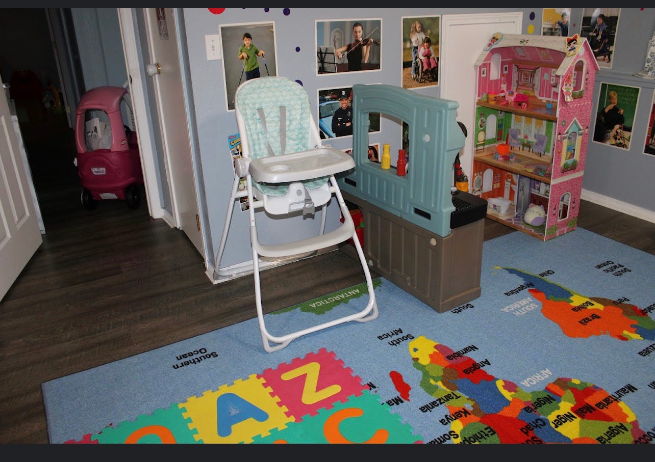 High chair, dollhouse, and play kitchen in a room with a world map rug