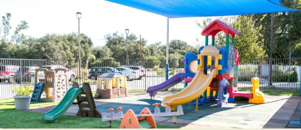 Outdoor playground with slides and play structures under a blue canopy
