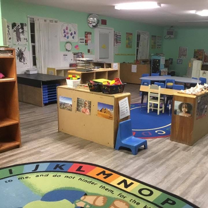 Classroom with tables, chairs, and an alphabet rug
