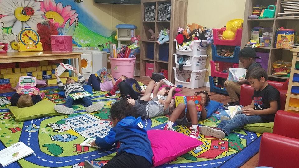 Children reading books on a colorful rug in a classroom